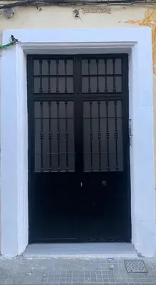 a black door in a white building at Apartamento El Arrumbador in Jerez de la Frontera