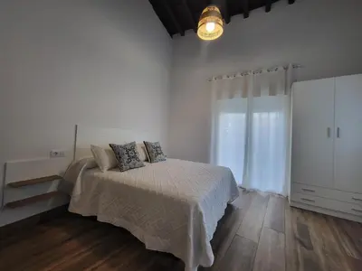 a white bedroom with a bed and a large window at Apartamento La Albariza in Jerez de la Frontera