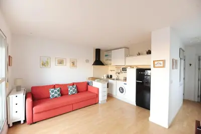 a living room with a red couch and a kitchen at Atico Brisa in Cádiz