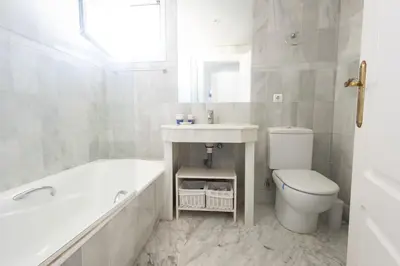 a white bathroom with a tub and a sink and a toilet at Ático Costa Ballena playa infante. 1º línea playa in Rota