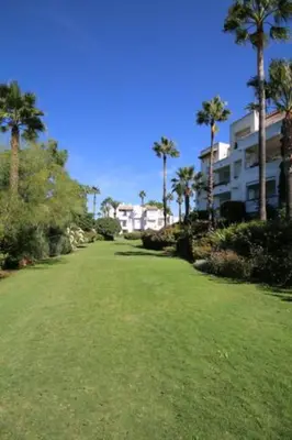 a large yard with palm trees and a building at Ático Costa Ballena playa infante. 1º línea playa in Rota