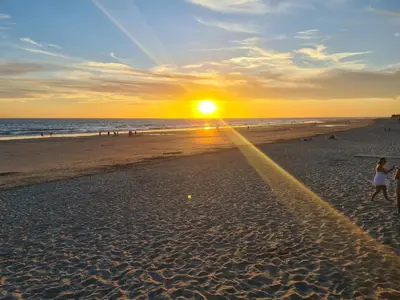 a group of people walking on the beach at sunset at Ático Costa Ballena playa infante. 1º línea playa in Rota