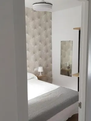 a bedroom with a white bed and a mirror at apartamentos Larios centro in Sanlúcar de Barrameda
