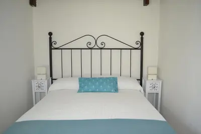 a bed with a black frame and a blue pillow at Alojamiento entero Valdelagrana in El Puerto de Santa María