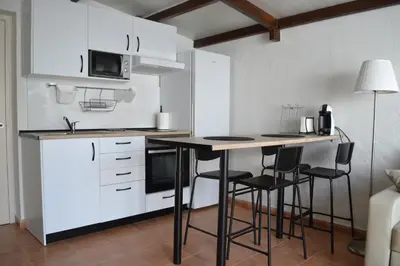 a kitchen with white cabinets and a table with stools at Alojamiento entero Valdelagrana in El Puerto de Santa María