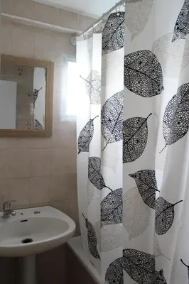 a bathroom with a sink and a shower curtain with umbrellas at Alojamiento Teja in Arcos de la Frontera