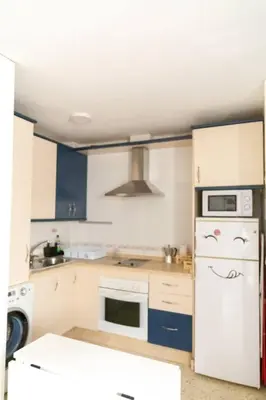 a kitchen with white appliances and blue cabinets at Pasquín in Cádiz