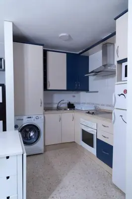 a kitchen with blue cabinets and a washing machine at Pasquín in Cádiz