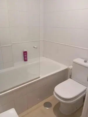 a white bathroom with a toilet and a bath tub at Apartamento Vallehermoso in El Puerto de Santa María