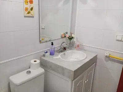 a bathroom with a sink and a mirror and a toilet at Apartamento Vallehermoso in El Puerto de Santa María