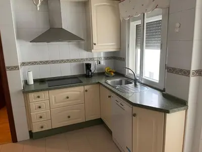 a kitchen with white cabinets and a sink and a window at Apartamento Vallehermoso in El Puerto de Santa María
