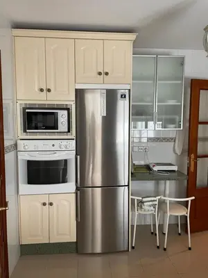 a kitchen with a stainless steel refrigerator and white cabinets at Apartamento Vallehermoso in El Puerto de Santa María