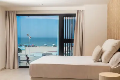 a bedroom with a bed and a view of the beach at Apartamentos Playa Victoria - by Grupo Tribu in Cádiz