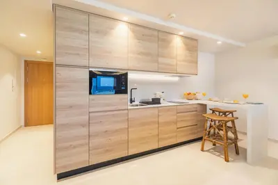 a kitchen with a large wall of wooden cabinets at Apartamentos Playa Victoria - by Grupo Tribu in Cádiz