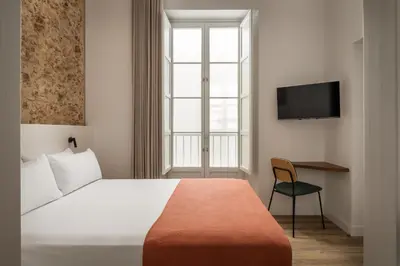 a hotel room with a bed and a television at BYPILLOW Casa Gades in Cádiz