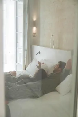 a man laying in a bed reading a book at BYPILLOW Casa Gades in Cádiz