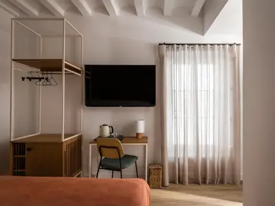 a bedroom with a bed and a desk with a television at BYPILLOW Casa Gades in Cádiz