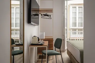 a bedroom with a bed and a desk and chairs at BYPILLOW Casa Gades in Cádiz
