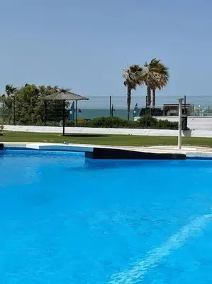 a large blue swimming pool next to the ocean at Apartamento Luz in Chiclana de la Frontera