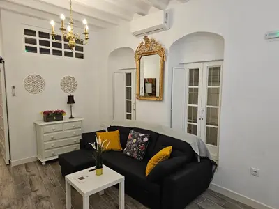 a living room with a black couch and a mirror at Apartamento Casa Pura in Medina Sidonia