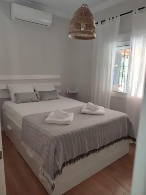 a white bedroom with a bed with two towels on it at EL RETIRO in Sanlúcar de Barrameda