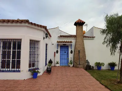 a white house with a blue door and a brick driveway at EL RETIRO in Sanlúcar de Barrameda