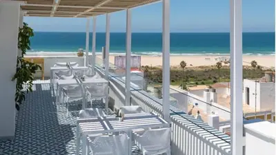a balcony with white chairs and a view of the beach at Casita Playa Conil in Conil de la Frontera