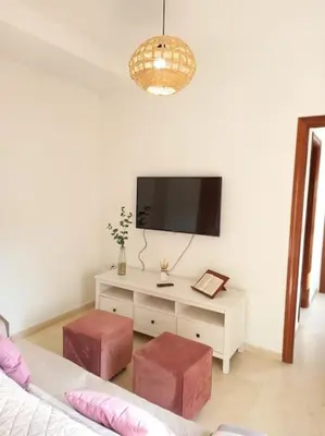 a living room with a tv and a table with two stools at Banda playa 82, en pleno corazón de Sanlucar in Sanlúcar de Barrameda
