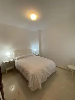 a white bedroom with a bed and two tables at Banda playa 82, en pleno corazón de Sanlucar in Sanlúcar de Barrameda