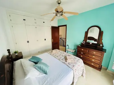 a bedroom with a bed with a ceiling fan and a mirror at Casa SOL y MAR junto a la PLAYA in Sanlúcar de Barrameda
