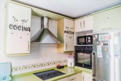 a kitchen with white cabinets and a stainless steel refrigerator at Casa SOL y MAR junto a la PLAYA in Sanlúcar de Barrameda