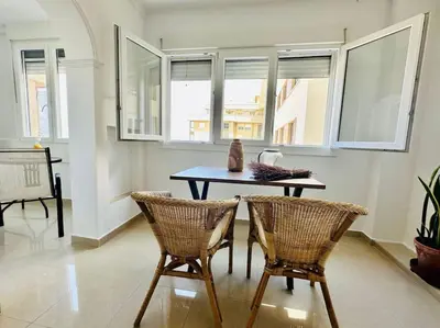 a table and two chairs in a room with windows at Apartamento a pie de playa. in Cádiz