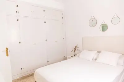 a white bedroom with a bed and white cabinets at Libertad by Gades Gestión in Cádiz