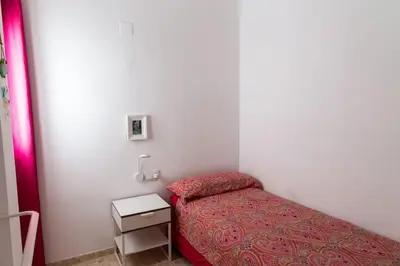 a small bedroom with a bed and a night stand at Libertad by Gades Gestión in Cádiz