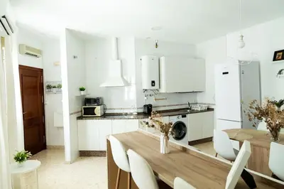 a white kitchen with a wooden table and white appliances at Libertad by Gades Gestión in Cádiz