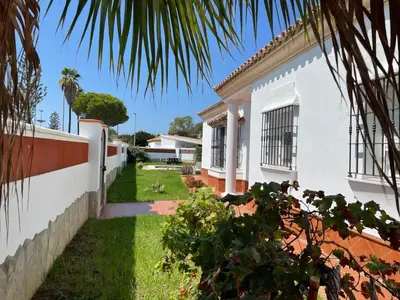 a white house with a fence and a yard at Chalet Manku in Chiclana de la Frontera