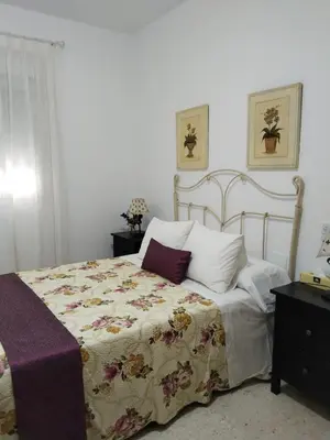 a bedroom with a bed with a floral bedspread at Piso vacacional en Sanlúcar in Sanlúcar de Barrameda