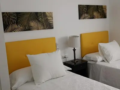 a bedroom with two beds and a yellow headboard at Piso vacacional en Sanlúcar in Sanlúcar de Barrameda