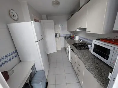 a small kitchen with white cabinets and a white refrigerator at La Almadraba in Novo Sancti Petri