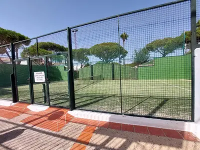 a chain link fence with a tennis court behind it at La Almadraba in Novo Sancti Petri
