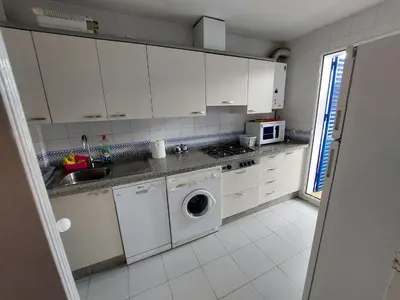 a kitchen with white cabinets and a washing machine at La Almadraba in Novo Sancti Petri