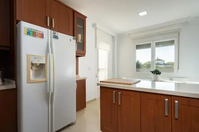 a kitchen with a white refrigerator and wooden cabinets at Apartoyou - Chalet & Pool in El Puerto de Santa María
