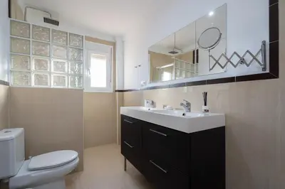 a bathroom with a sink and a toilet and a mirror at Apartoyou - Chalet & Pool in El Puerto de Santa María