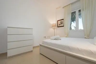 a white bedroom with a bed and a window at Apartoyou - Chalet & Pool in El Puerto de Santa María