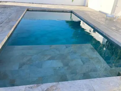 a swimming pool with a stone floor and blue water at Villa El Lagar in Novo Sancti Petri