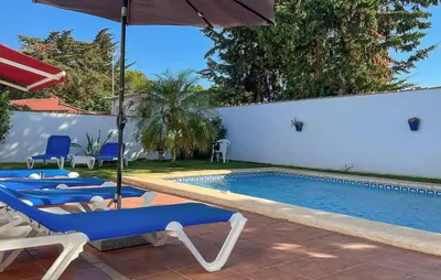 a swimming pool with blue chairs and an umbrella at Gorgeous Home In Chiclana De La Fronter in Chiclana de la Frontera