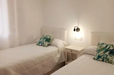 a small room with two beds and a night stand at Fernando de Magallanes 15, Bajo en segunda línea de playa in Sanlúcar de Barrameda