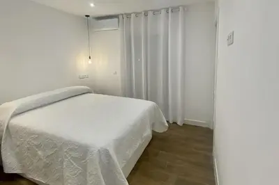 a bedroom with a white bed and white curtains at Fernando de Magallanes 15, Bajo en segunda línea de playa in Sanlúcar de Barrameda
