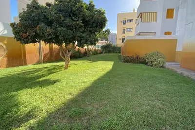 a green yard with a tree and a building at Fernando de Magallanes 15, Bajo en segunda línea de playa in Sanlúcar de Barrameda