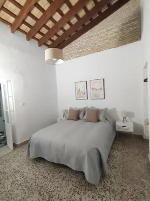 a white bedroom with a large bed and a brick wall at Apartamentos Casa Vicario in Jerez de la Frontera